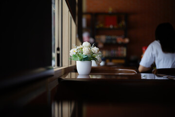 Flowers in a vase on wood table in a coffee shop.