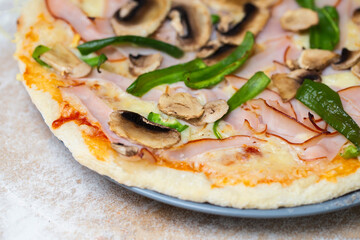 Delicious homemade pizza with ham, bell pepper, and mushrooms on wooden cutting board. Freshly baked pizza with flour all around. Do it yourself piza at home background. Big plate of thin crust pizza.
