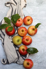 Fresh red and yellow apples with leaves on grey background, top view