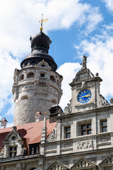 Obraz premium Portrait format shot of the town hall tower and blue illuminated clock on the facade of the New Town Hall in Leipzig. Latin lettering around the clock. Building in historicist style.