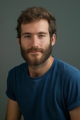 Fototapeta premium A portrait of a bearded man in a blue shirt against a neutral background, conveying confidence and simplicity. Ideal for portrait, fashion, and lifestyle-themed projects.