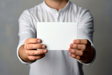 A person wearing a white shirt holding a blank card with both hands extended forward