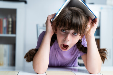 girl bored of studying with a book on her head