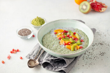 Matcha chia puddind with fruit berry salad in bowl on grey background. Healthy breakfast