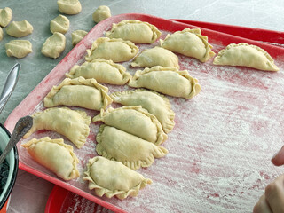 Cooking dumplings with blueberries. Dumplings are laid out on a tray.
