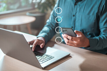 mobile, app, smartphone, commerce, professional, global, marketing, information, social, corporate. A man is using a laptop and a cell phone. The laptop has a check mark on it.