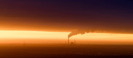 Fototapeta premium Sunrise over Industrial Factory Emitting Smoke, Stunning Contrast of Natural and Polluted Sky
