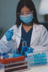 Group of dedicated scientist conduct chemical experiment in medical laboratory, carefully drop precise amount of liquid from pipette into test tube for vaccine drug or antibiotic development. Neoteric