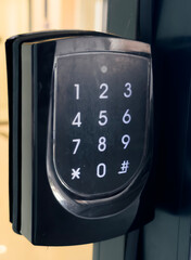 A close-up of a black keypad door lock with a numerical keypad.