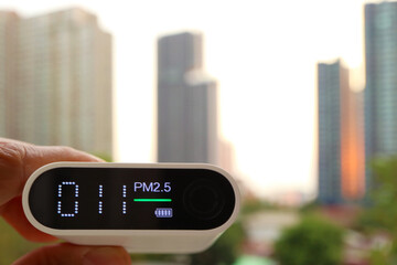 Hand holding an air quality sensor with group of skyscrapers in the backdrop