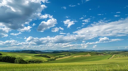 Fototapeta premium Rolling Green Hills Under a Blue Sky with White Clouds.