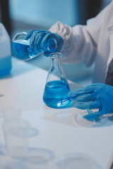 Group of dedicated scientist conduct chemical experiment in medical laboratory, carefully drop precise amount of liquid from pipette into test tube for vaccine drug or antibiotic development. Neoteric