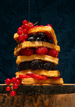 Waffles with fresh summer berries on a dark blue floral background