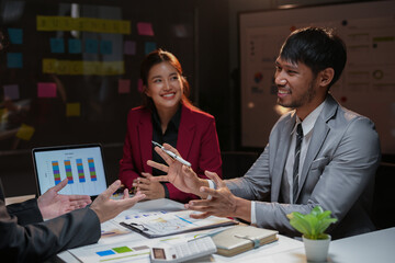 Late night business team brainstorming new ideas and analyzing financial data on laptop and document