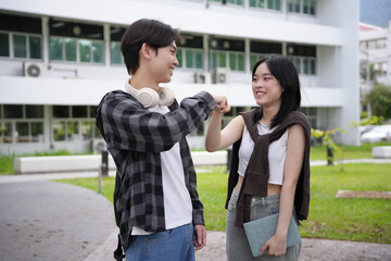 Excited students fist bumping on campus, happy to be back to school. Embracing learning, teamwork, and success. Youthful energy and school spirit