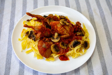 Quail prepared on a plate with pasta and egg crumbs