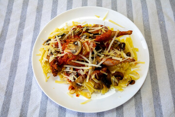 Quail prepared on a plate with pasta and egg crumbs