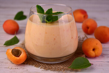 Apricot smoothie in a glass on a white wooden table.Close-up.	