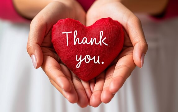 Close-up of hands holding a red heart with 'Thank you' written on it. Perfect for expressing gratitude in various projects, including cards and social media.