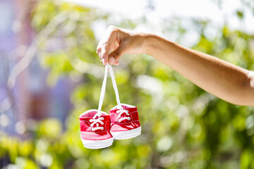 A hand holding red baby shoes