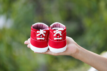 A hand holding red baby shoes