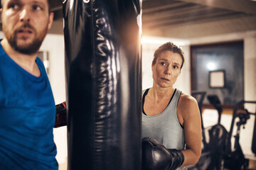 Woman and a partner working out with a boxing gym punching bag