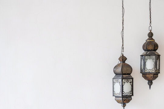 Two antique lanterns hanging against a white background, creating a minimalist and elegant look