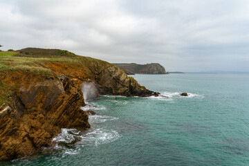 Fototapeta premium Falaises escarpées et eaux couleur émeraude sous un ciel nuageux, lors d'une journée automnale sur la presqu'île de Crozon.