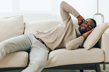 Relaxed African American Man Sitting on Sofa, Smiling and Enjoying a Weekend at Home