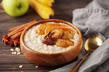 Oatmeal porridge with caramelised apples and bananas in bowl on the table. Homemade healthy breakfast