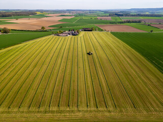 Aerial drone shot of farmer with tractor making hay on field in rural southern Germany