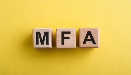 Obraz premium Wooden cubes with abbreviation MFA, yellow background. Multi-Factor Authentication. Online security