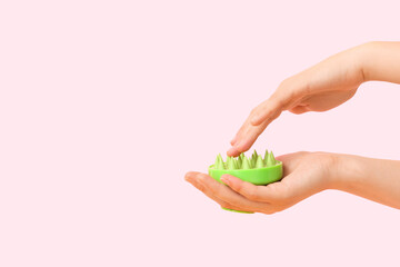 Female hands with silicone head massage brush on pink background