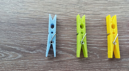 Three plastic clothespins in blue, green and yellow.