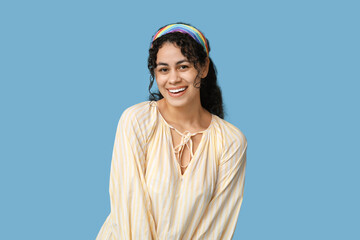 Pretty African-American woman wearing dress and headband on blue background