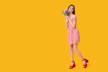 Happy smiling young woman with hyacinth flowers on yellow background