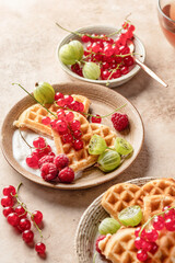 Homemade waffles with summer berries and yogurt served for sweet breakfast with tea on beige background. Heart shaped waffles