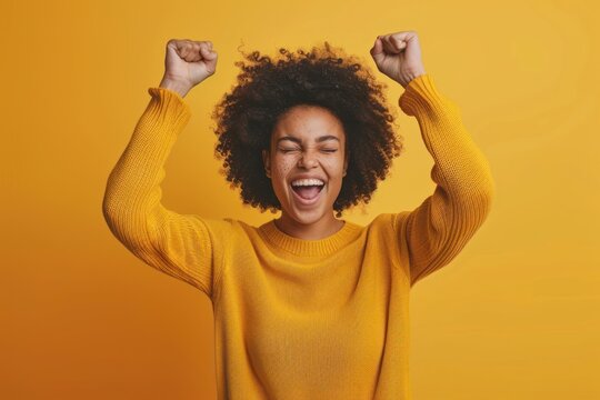 Feeling Ecstatic, A Happy Young Woman with Raised Fists on a solid color Background
