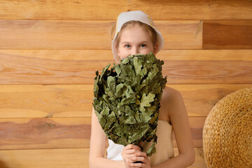 Young woman with whisk in sauna