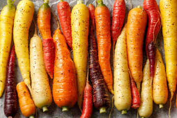 Ready to bake rainbow carrots on a parchment lined baking sheet.