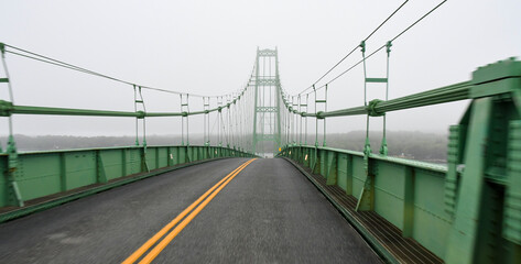 The Deer Isle Bridge in Sedgwick, Maine on a foggy morning as it spans across Eggemoggins Reach to...