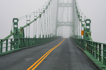 The Deer Isle Bridge in Sedgwick, Maine on a foggy morning as it spans across Eggemoggins Reach to...