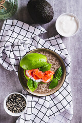 Avocado keto burger with red fish, radishes and sauce on a plate on the table top and vertical view