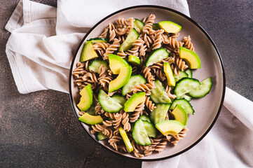Close up of delicious salad of buckwheat pasta, cucumber and avocado on a plate top view
