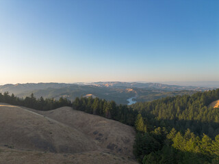 View of golden hour sunset over mountains with trees and horizon line