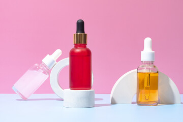 Vibrant dropper bottles on modern podium set against a pink backdrop