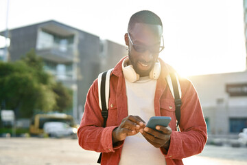 Cool young happy African Black man hipster student or tourist wearing sunglasses and backpack...