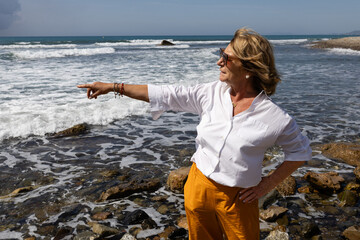 Senior woman pointing and enjoying Mediterranean coast views