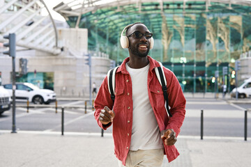 Happy cool stylish young African Black man student hipster wearing headphones, sunglasses and...