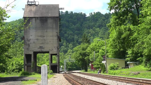 WEST VIRGINIA - 7.5.2024 - A man and child walk along the empty train tracks of a West Virginia ghost town, towards a forest.